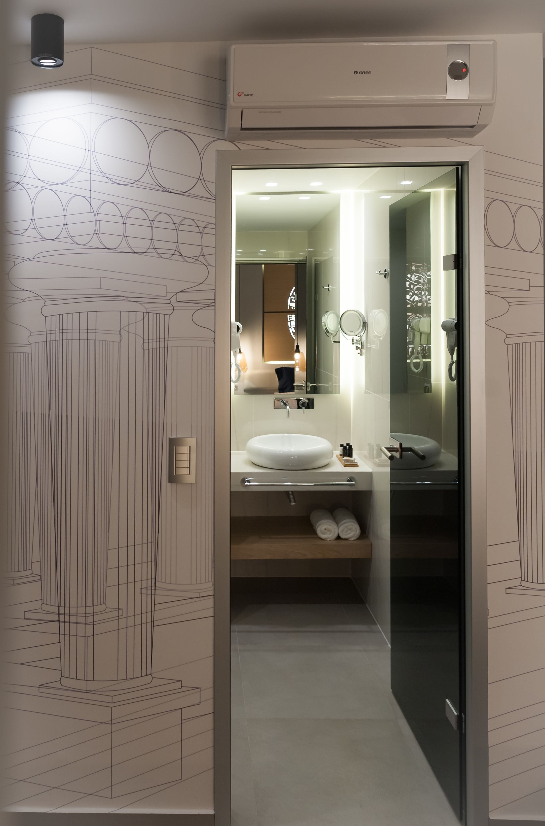 A modern bathroom with a large mirror, two sinks, and a toilet.