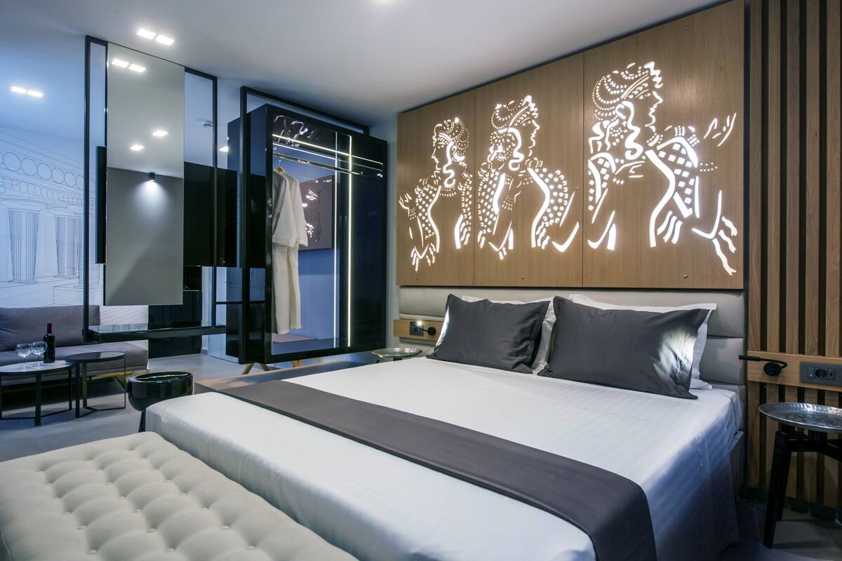 Ein modernes Hotelzimmer mit einem großen Bett, einer Glastrennwand und einem dekorativen Wandbild.