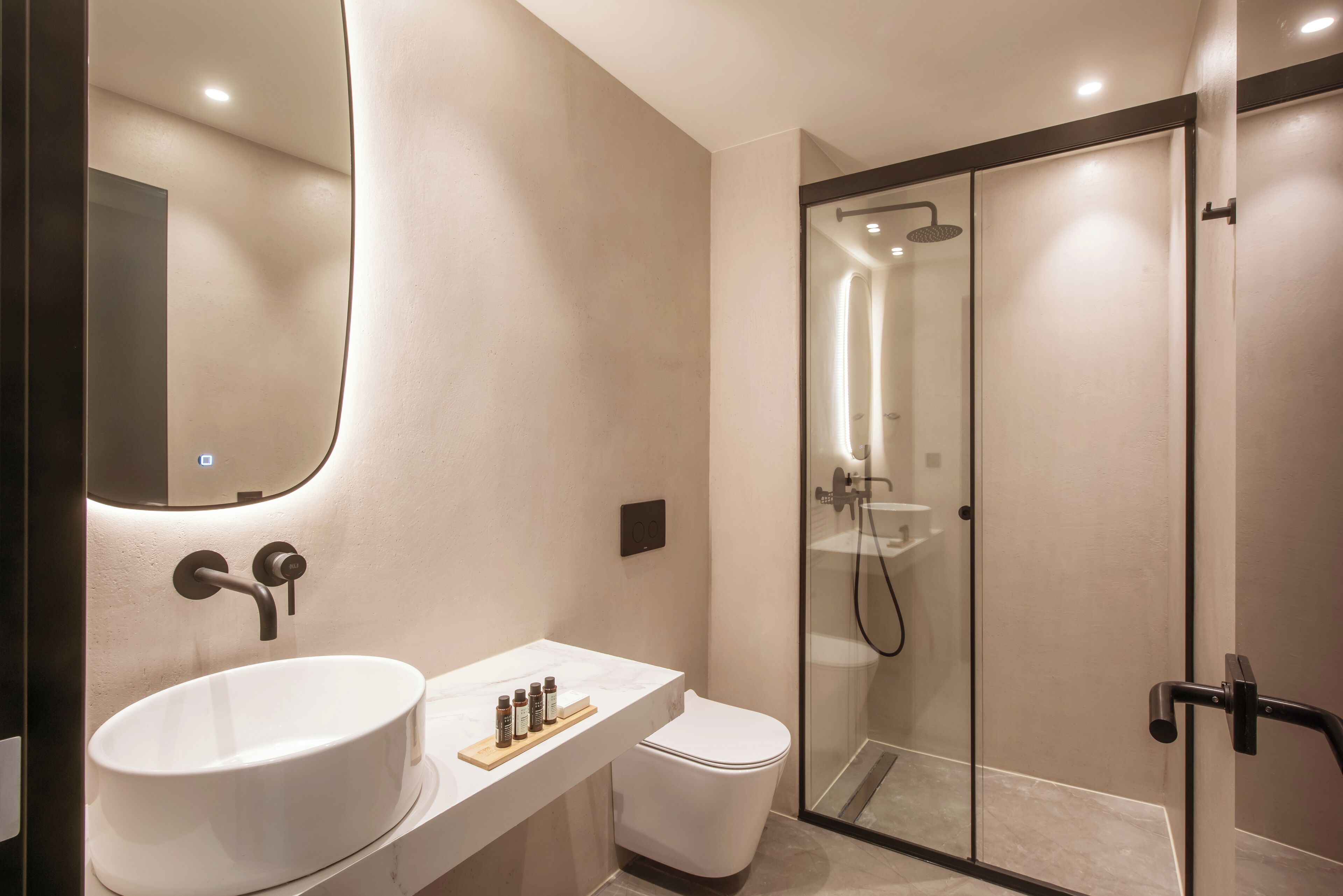 A modern bathroom with a large white sink, a toilet, and a glass-enclosed shower area.