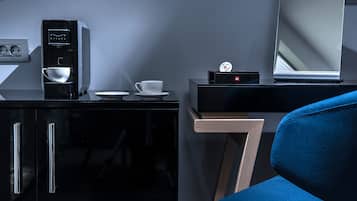 A modern room with a black cabinet, a coffee machine, a cup, a small table, and a blue chair.
