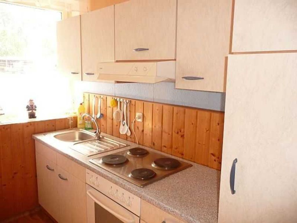 A kitchen with wooden cabinets, a stainless steel sink, and a stove.