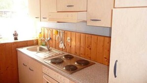 A kitchen with wooden cabinets, a stainless steel sink, and a stove. - Room 1 - Rügen apartment 52 (Schaprode auf Rügen)