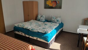 A bedroom with a bed, a wardrobe, a small table, and a painting of a butterfly. - Room 1 - Rügen apartment 52 (Schaprode auf Rügen)
