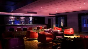 Un espace bar avec des sièges rouges et un barman.