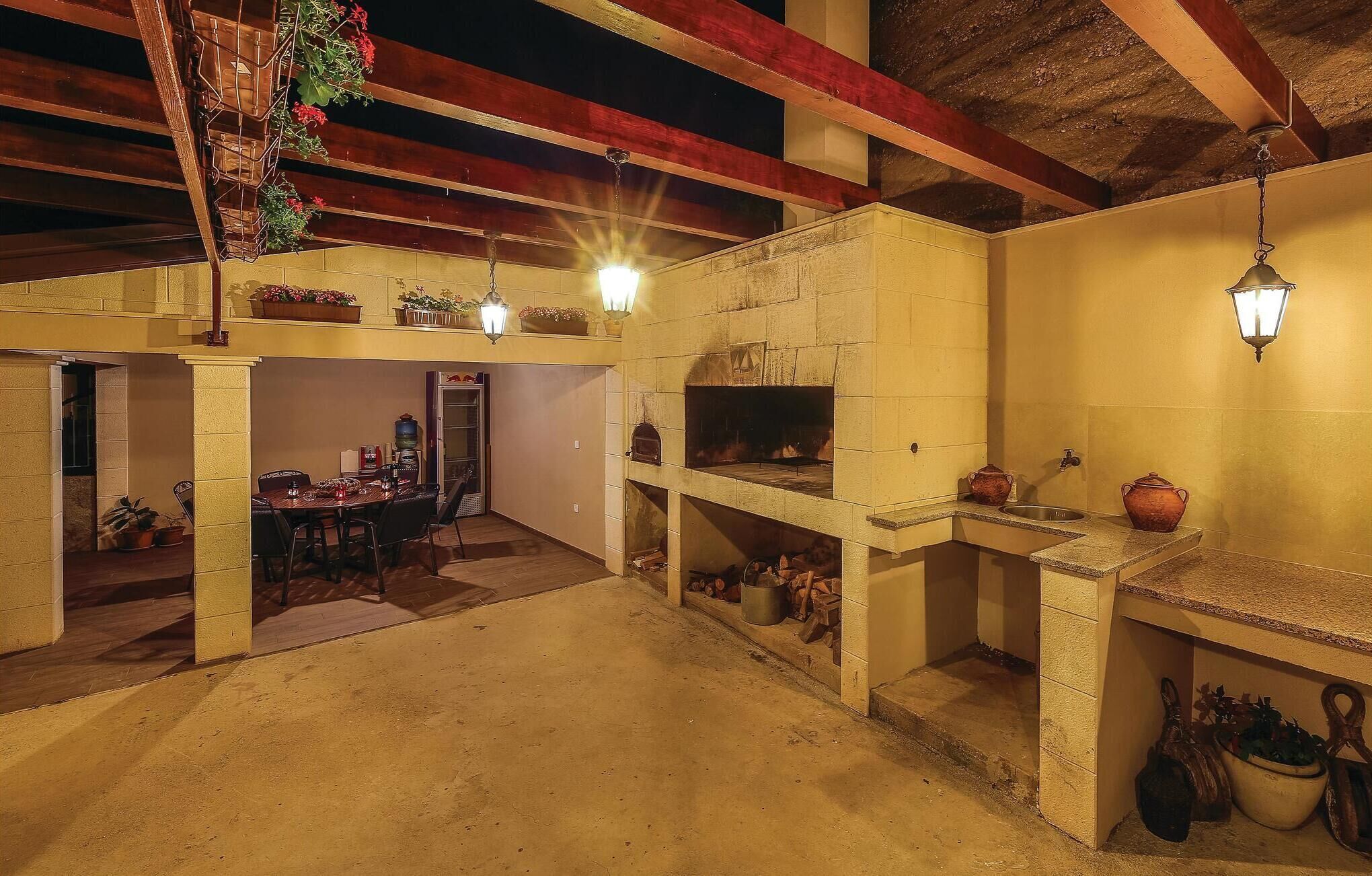 A rustic kitchen with a wood-burning stove, a dining area, and a sink with pots.