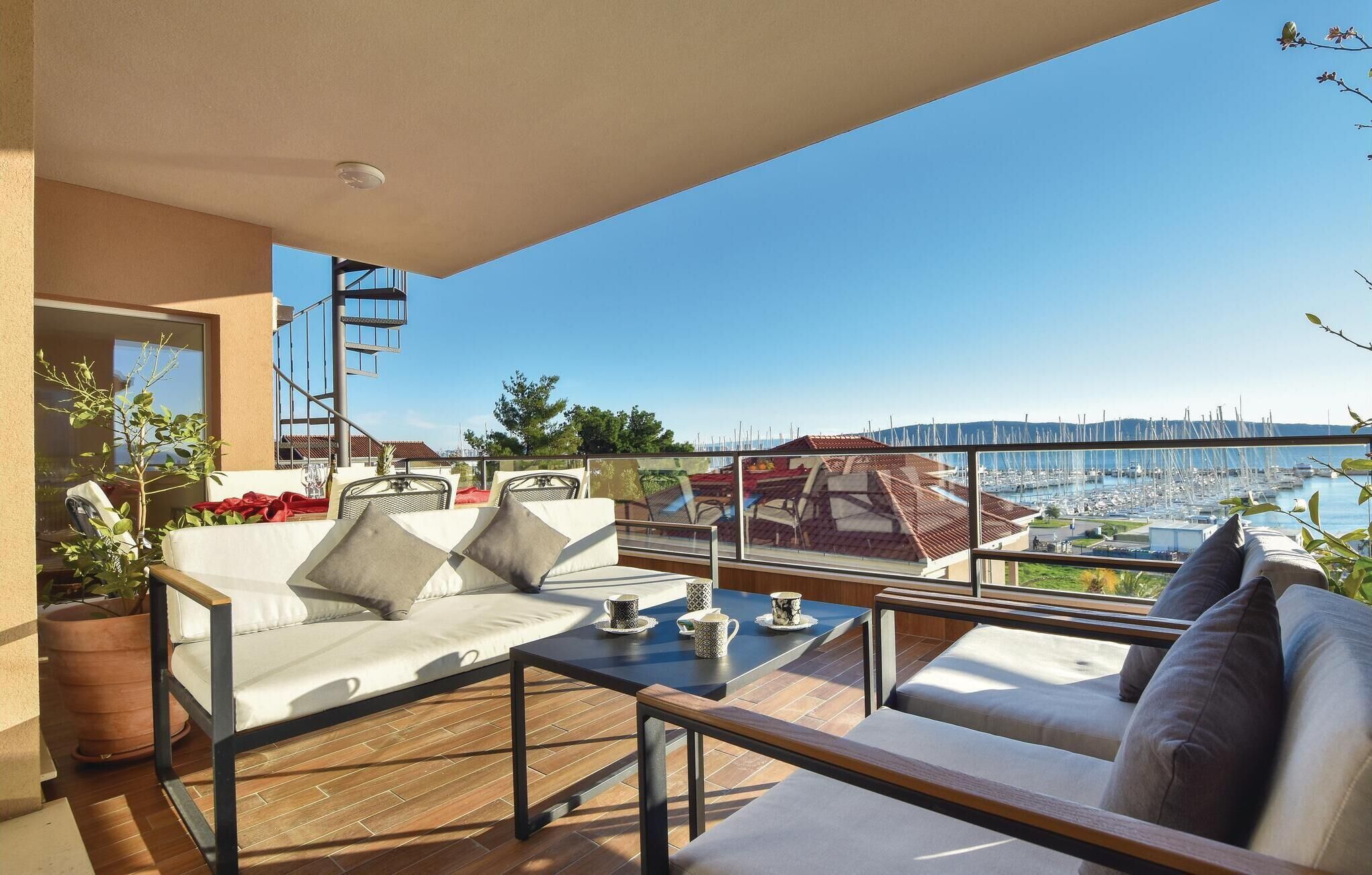 Un balcon avec un canapé, une table avec des tasses et une vue sur un port de plaisance.