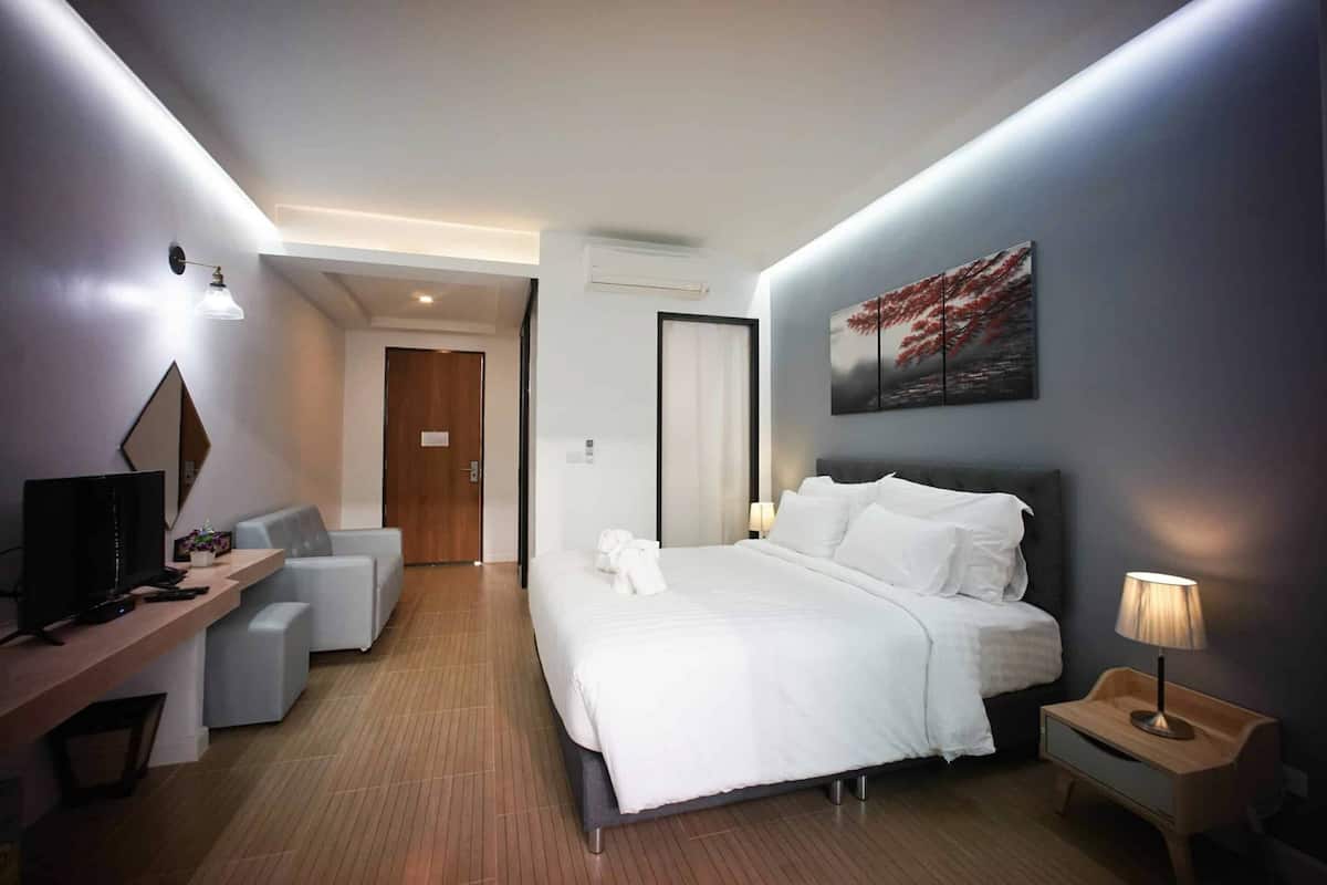 Une chambre d’hôtel moderne dotée d’un grand lit, d’un bureau avec une télévision, d’un coin salon et d’un tableau au mur.
