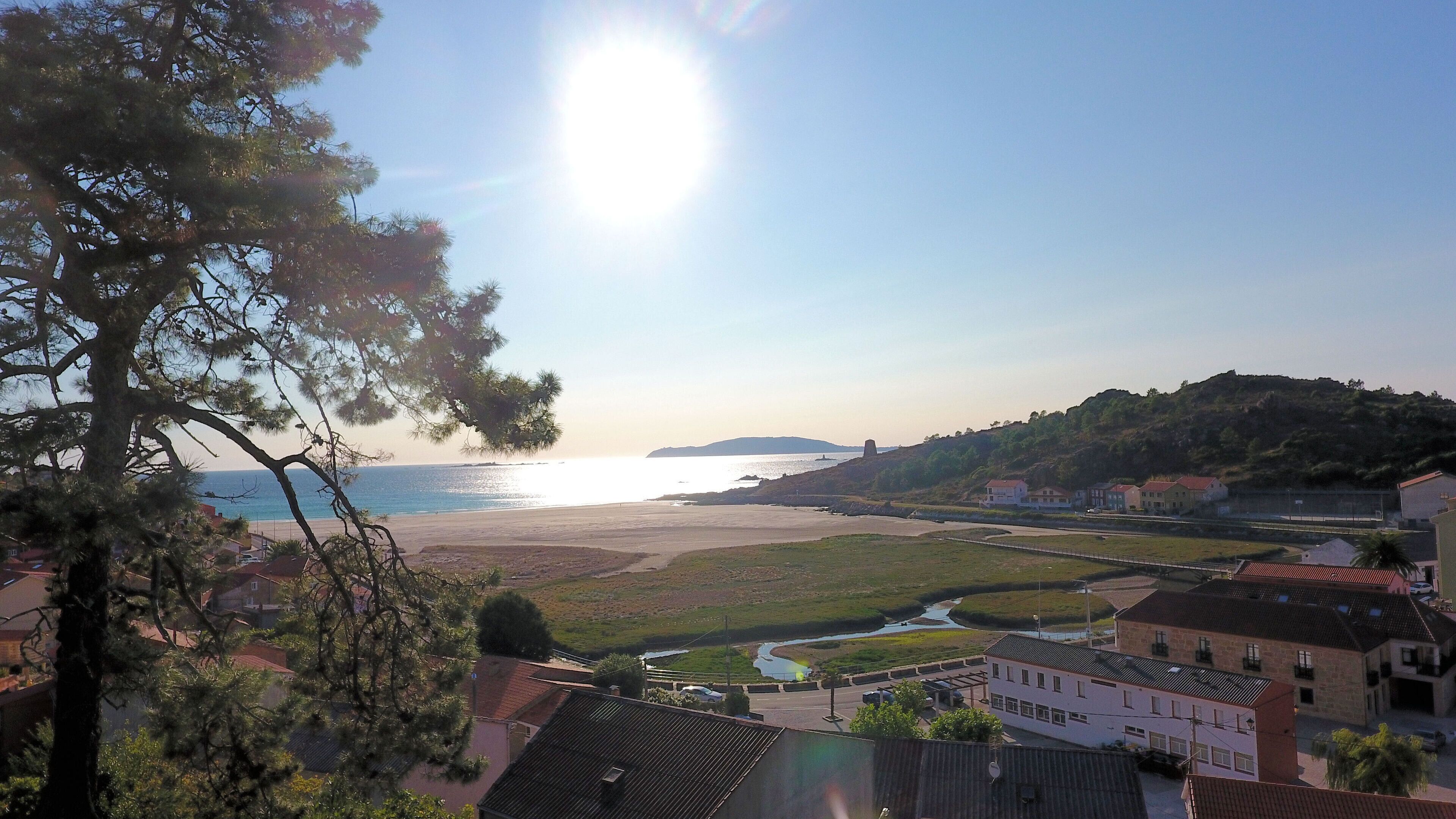 A coastal landscape with a beach, a river, and residential buildings.
