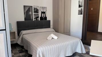 A bedroom with a bed, a wardrobe, and a nightstand.