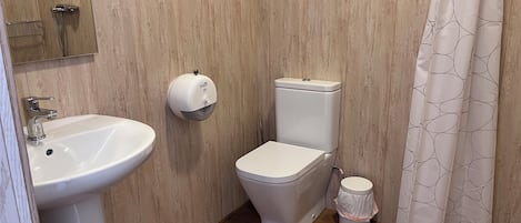 Ett badrum med handfat, toalett och duschdraperi.