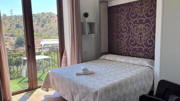 Un dormitorio con cama, vistas a un balcón y una pared decorada.