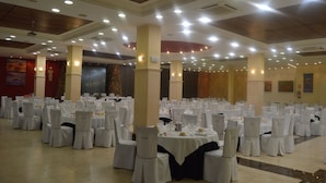 A banquet hall with round tables and white chairs, arranged in rows. - Balcones de Bentomiz (Arenas)