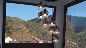 A balcony with a view of a hilly landscape, a hanging decorative light fixture, and a metal railing. - Balcones de Bentomiz (Arenas)