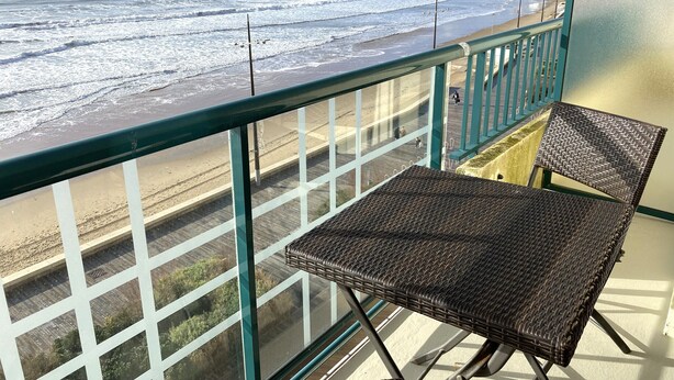 A balcony with a view of the beach and ocean, featuring two wicker chairs and a railing. - Seaside studio with balcony, 50m from the beach (Les Sables-d'Olonne)
