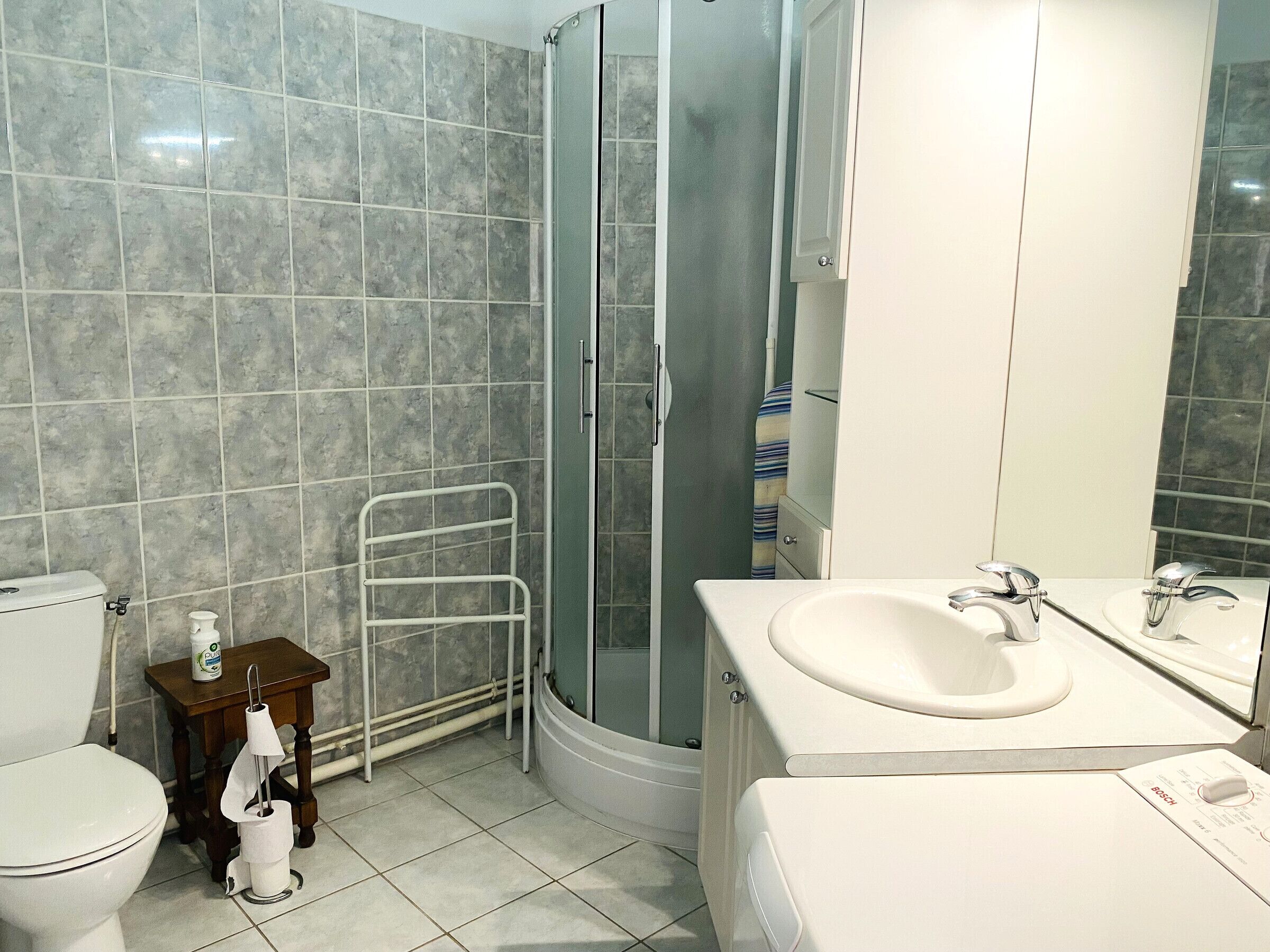 Een badkamer met toilet, wastafel, douche en een handdoekhouder.