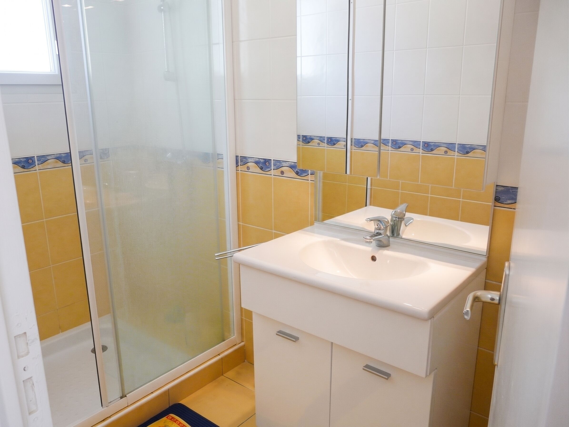 Un baño con ducha, lavamanos y espejo.