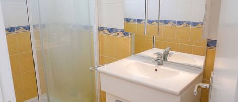 Un baño con ducha, lavamanos y espejo.