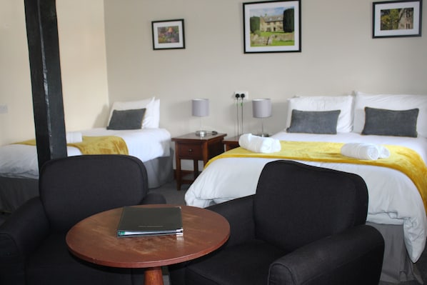Habitación de hotel con dos camas, una mesita y dos sillas.