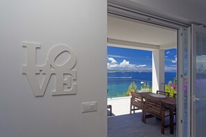 Un interior moderno con un cartel con la palabra 'LOVE', un balcón con mesa y sillas y vistas al mar.