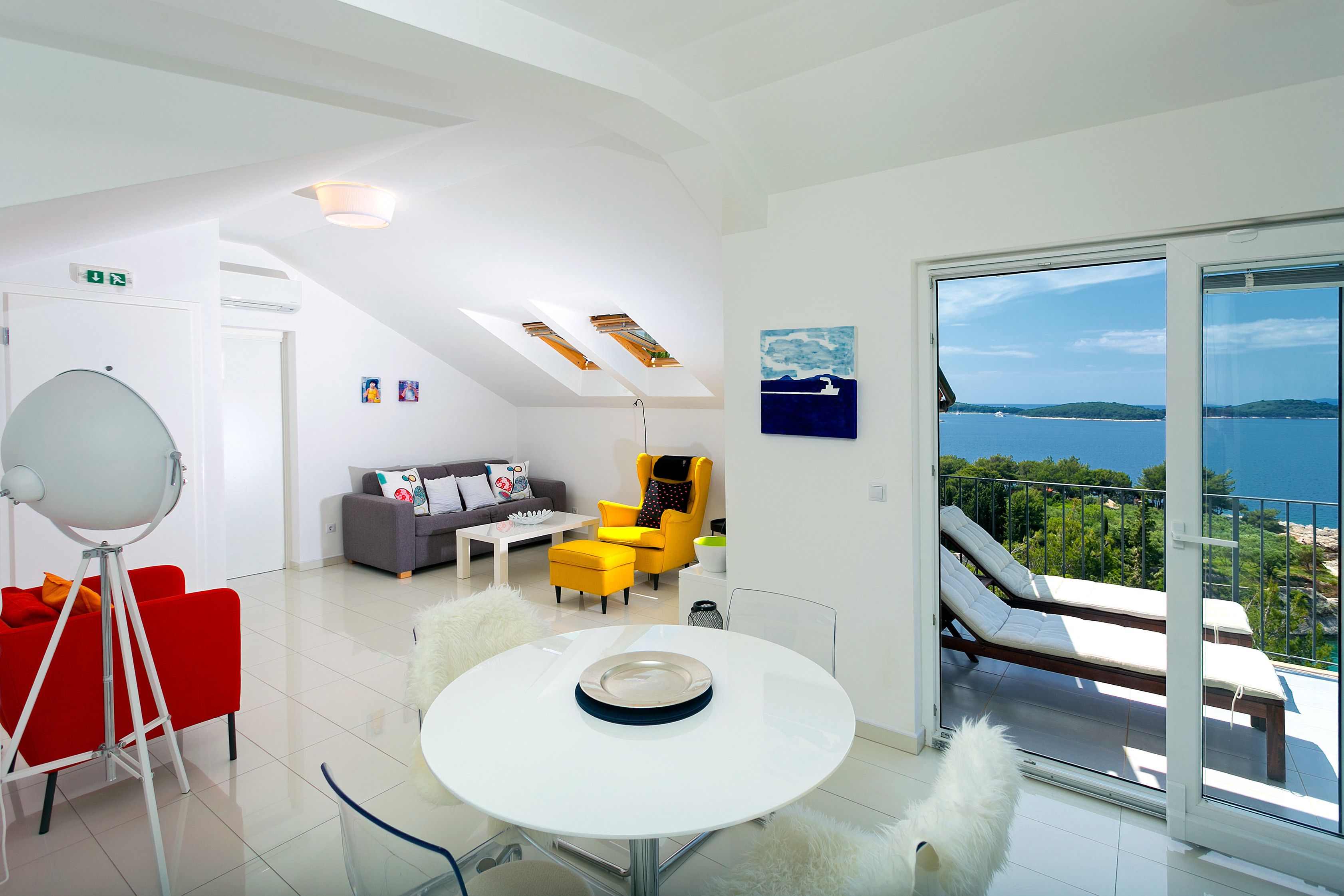 A modern living room with a balcony overlooking a body of water.