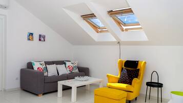 A modern living room with a grey sofa, a yellow armchair, a white coffee table, and a skylight above.