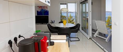A modern kitchen with a dining area, a coffee machine, and a view of the sea.