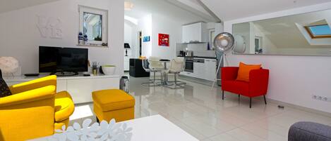 Una sala de estar moderna con sofás amarillos y grises, una mesa de centro blanca y un sillón rojo.