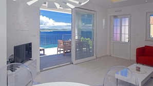 A modern living room with a balcony, a flat-screen TV, and a red sofa. - Blue Bay Residence (Hvar)