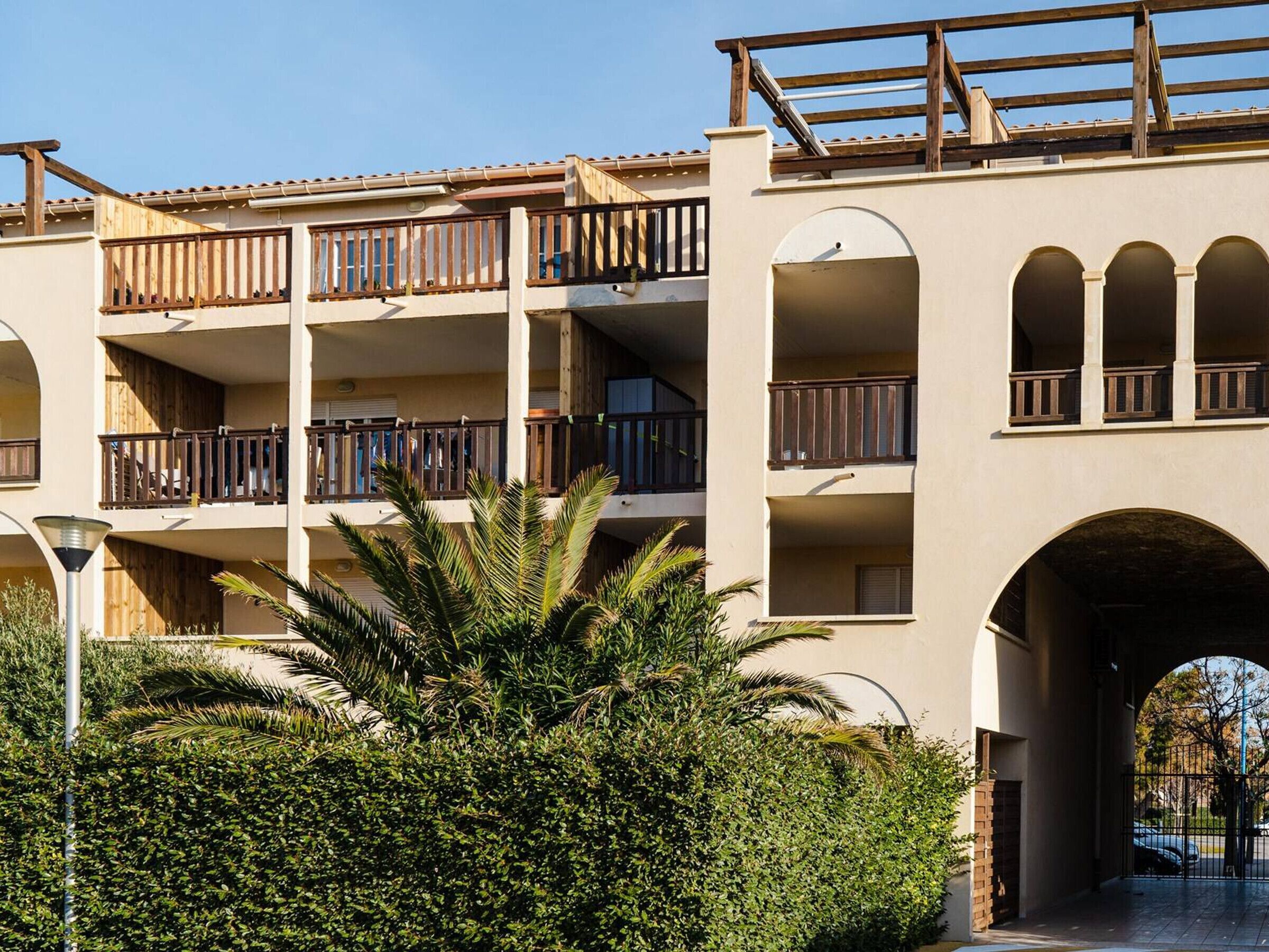 A multi-story hotel with balconies, a covered entrance, and a landscaped area with palm trees.