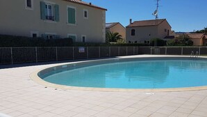 A swimming pool with a tiled deck, surrounded by a metal fence. - Cozy A/C 2BR Apartment with Pool near Beach, Shops - Narbonne-Plage (Narbonne)