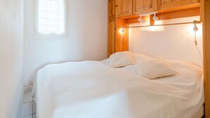 Et soveværelse med en seng, træskabe, et vindue med persienner og en lampe i loftet.