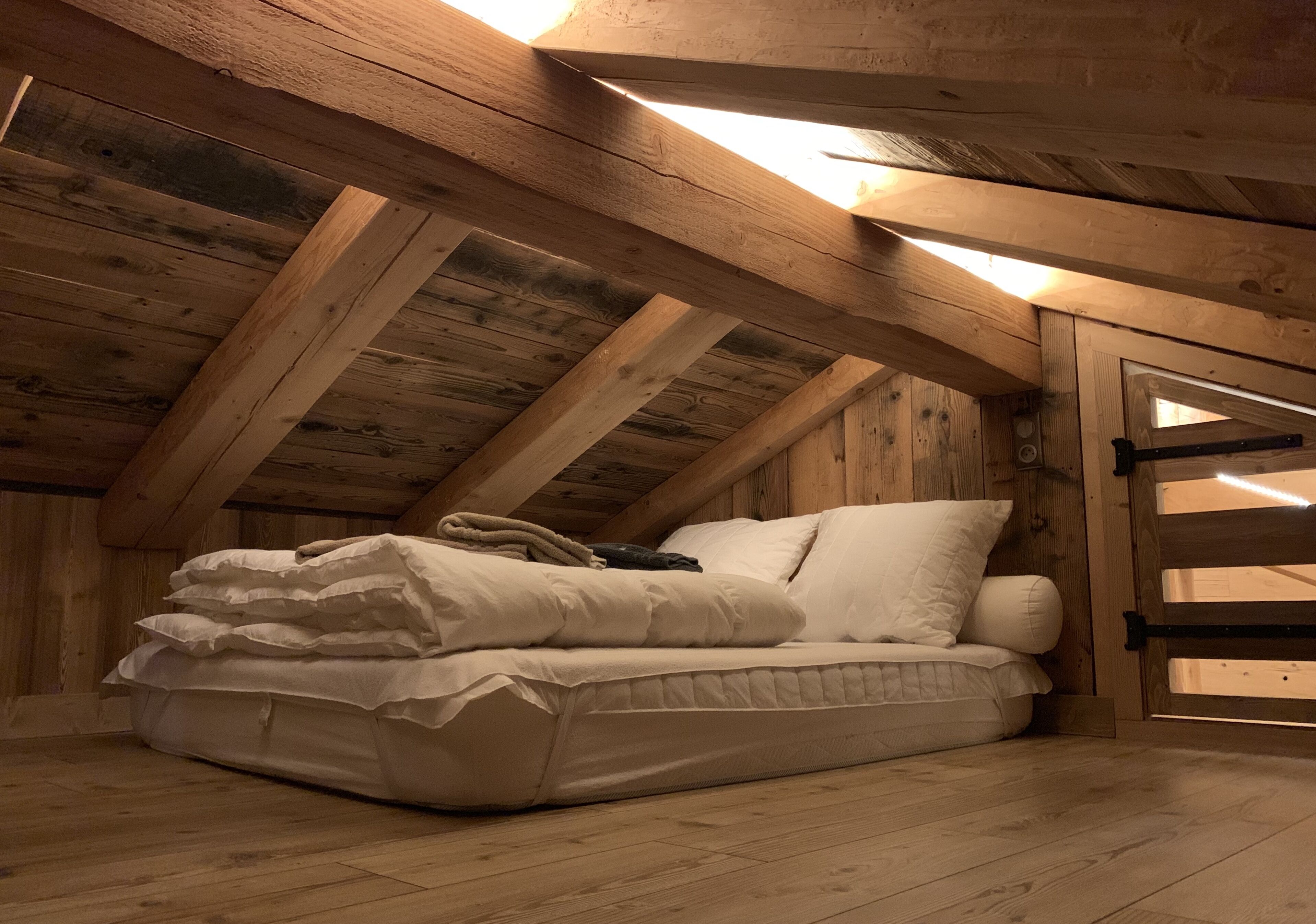 Slaapkamer in een loft met een houten plafond en een bed met witte beddengoed.