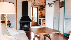Een knusse woonkamer met een open haard, een houten tafel en een bank.