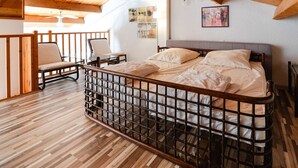 Een slaapkamer met een houten plafond, een bed met metalen frame, een stoel en een tafel.