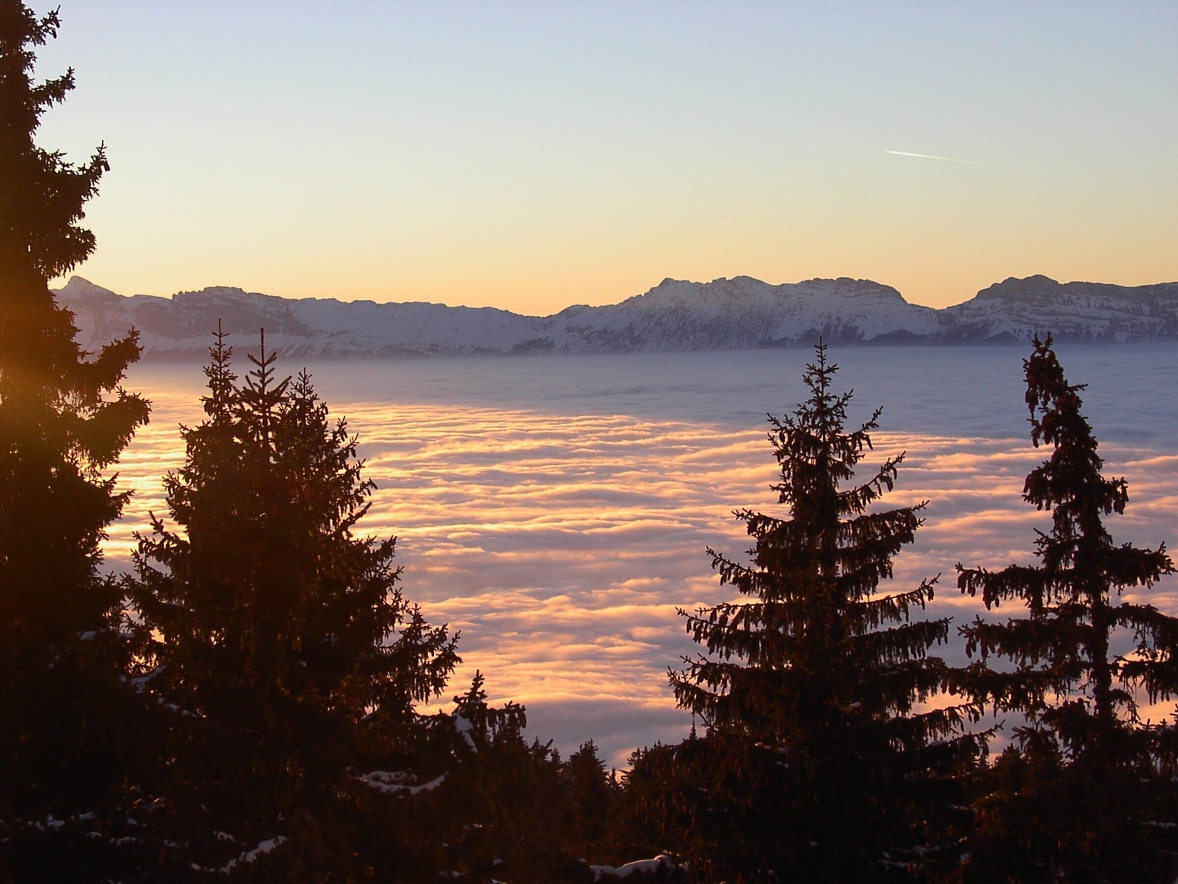 A mountainous landscape with snow-covered peaks and a view of the sky.