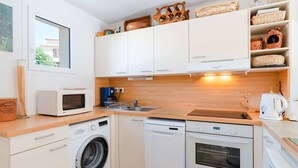Een praktische keuken met een wasmachine, vaatwasser, magnetron en oven.