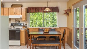 A kitchen with wooden cabinets, a stove, and a dining table with chairs.
