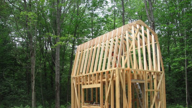 A wooden cabin structure in a forest, surrounded by trees.