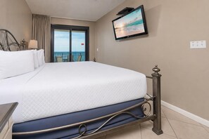 Habitación de hotel con cama, televisión, vista al mar y balcón.