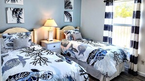 Ein Schlafzimmer mit zwei Betten, einem Deckenventilator und Bildern an den Wänden.