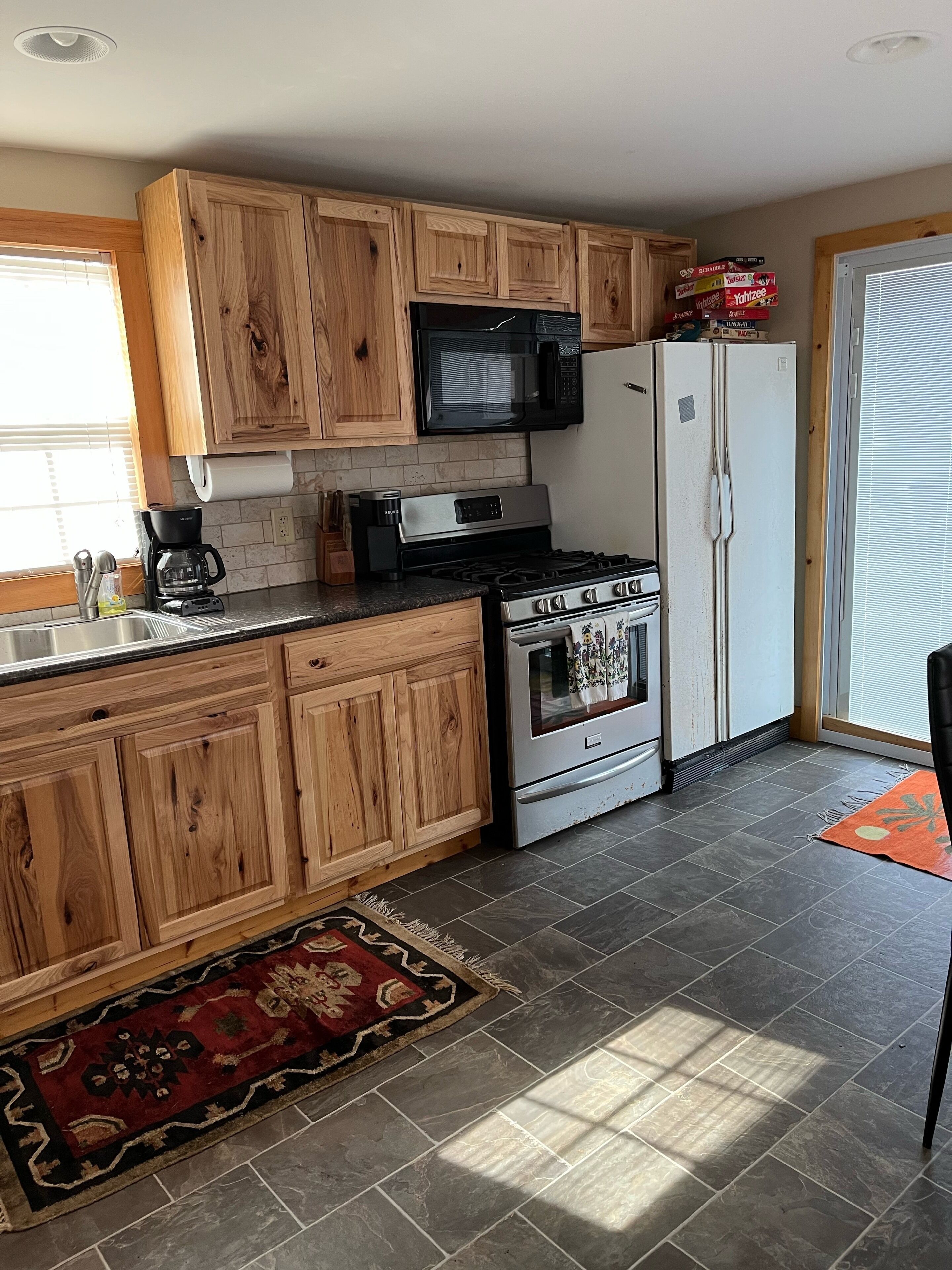 A kitchen with wooden cabinets, a stainless steel stove, a microwave, and a refrigerator.