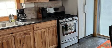 A kitchen with wooden cabinets, a stainless steel stove, a microwave, and a refrigerator.