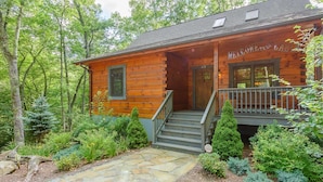 A wooden cabin with a porch, stone pathway, and surrounding greenery. - Private Creekside Cabin with Hot Tub (Fleetwood)