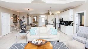 A spacious living room with a white sofa, a coffee table, and a dining area with a chandelier.