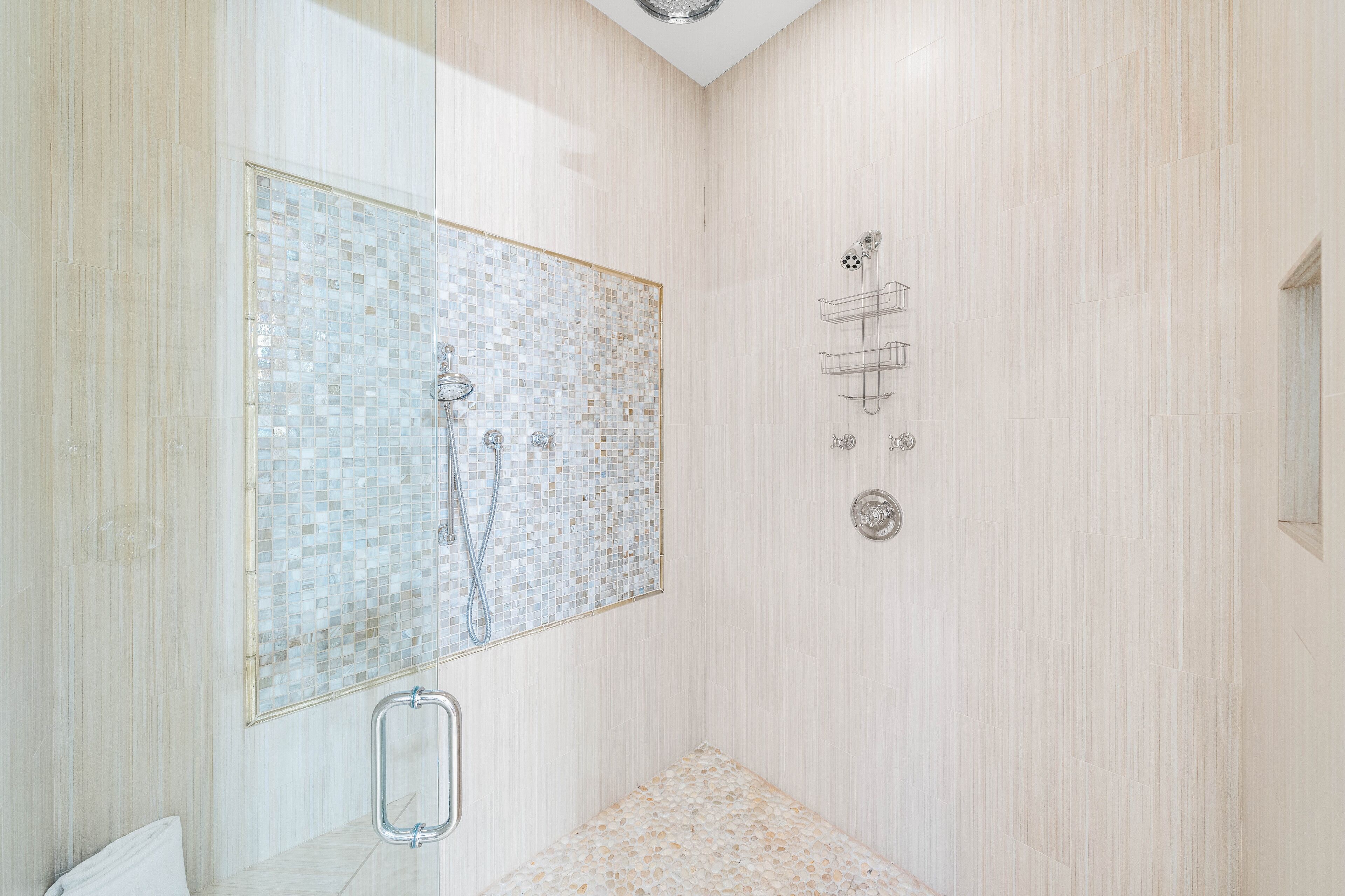 A modern bathroom with a glass-enclosed shower, a vanity with a mirror, and a tiled floor.