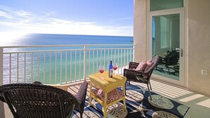 Ein Balkon mit Korbmöbeln, einem Tisch mit Weingläsern und Blick aufs Meer.