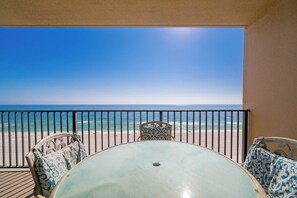 Ein Balkon mit Tisch und Stühlen mit Blick auf einen Strand und das Meer.
