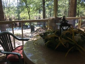 A covered outdoor seating area with a table, chairs, and a lantern. - The Duke's River House (Claxton)