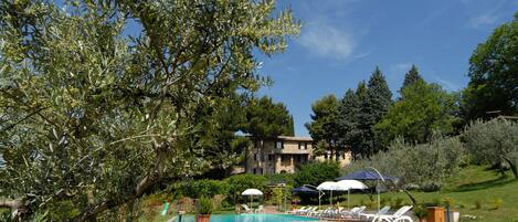 Een buitenzwembad, parasols bij het zwembad en ligstoelen