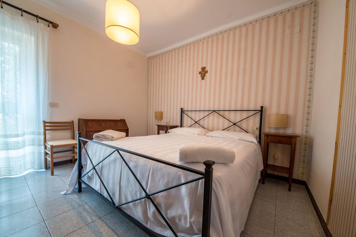 A neatly arranged bedroom with a bed, a chair, a bedside table, and a lamp.